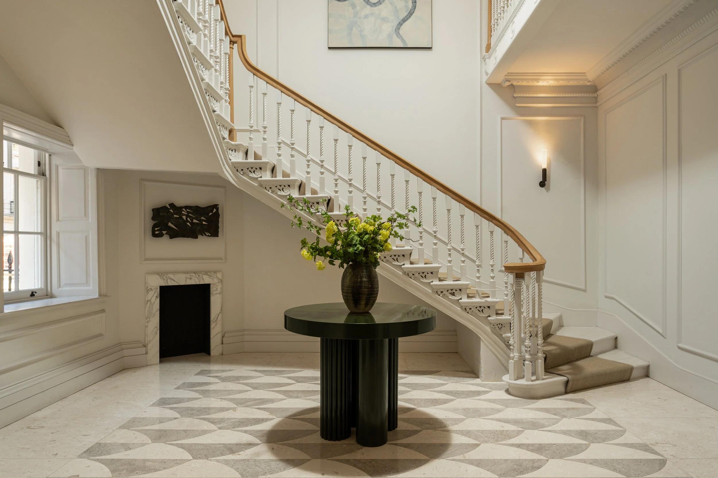 Elegant light-filled townhouse entrance hall with sweeping white staircase and balustrades