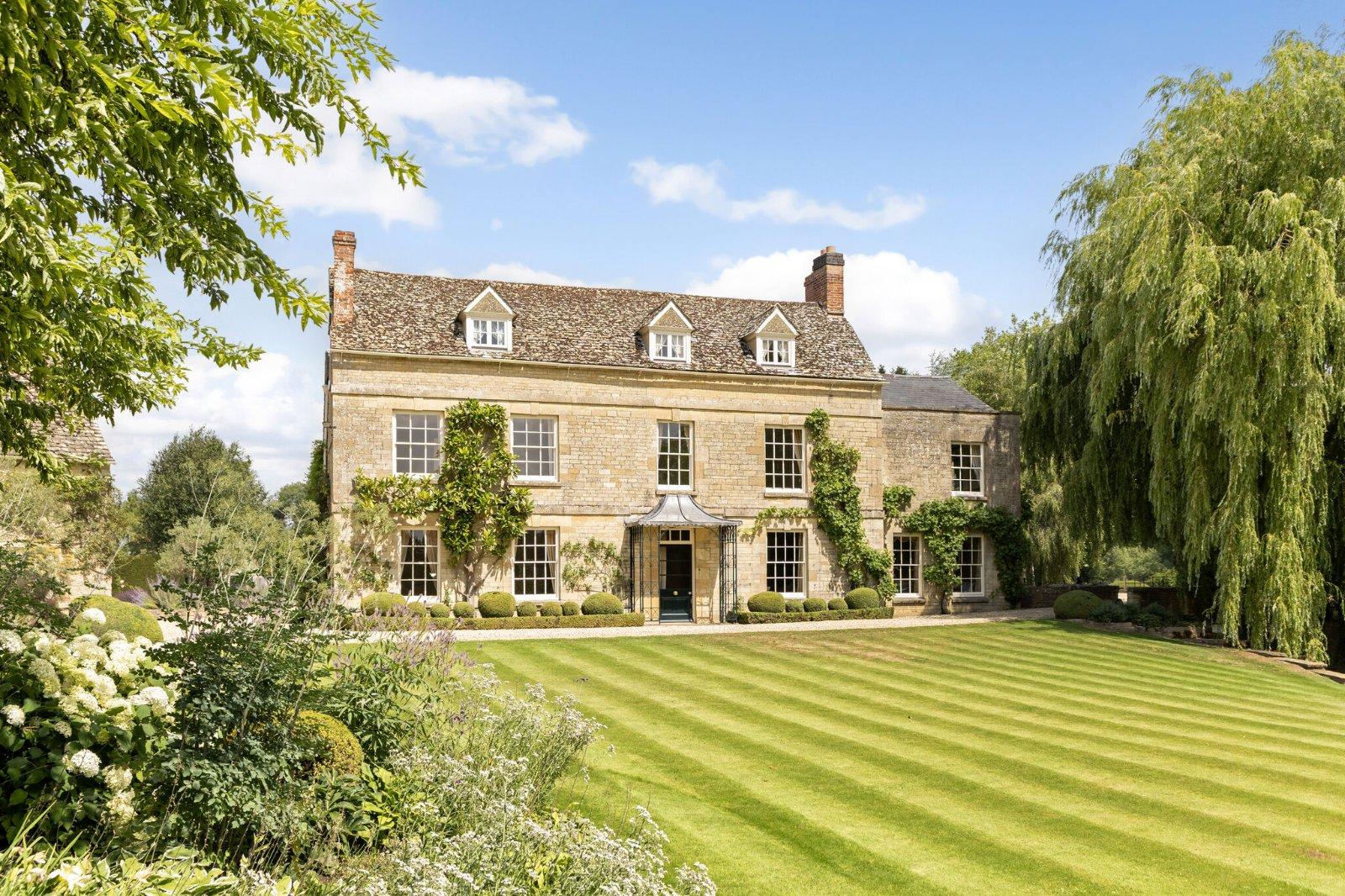 Sunlit Cotswolds stone country residence with a manicured lawn